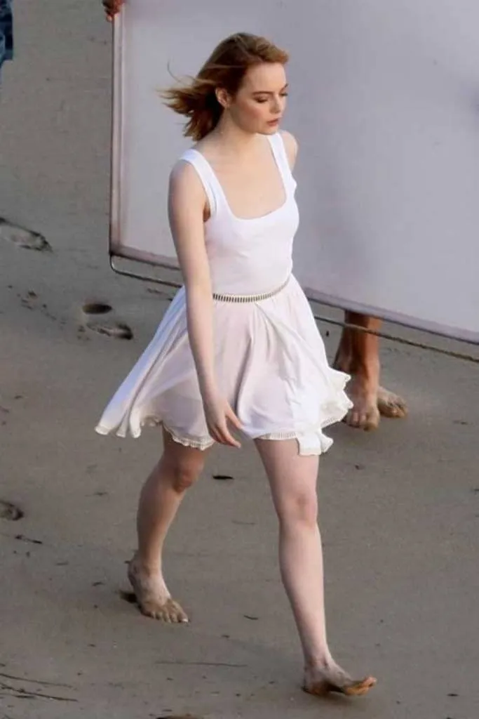Emma Stone walking on the beach barefoot